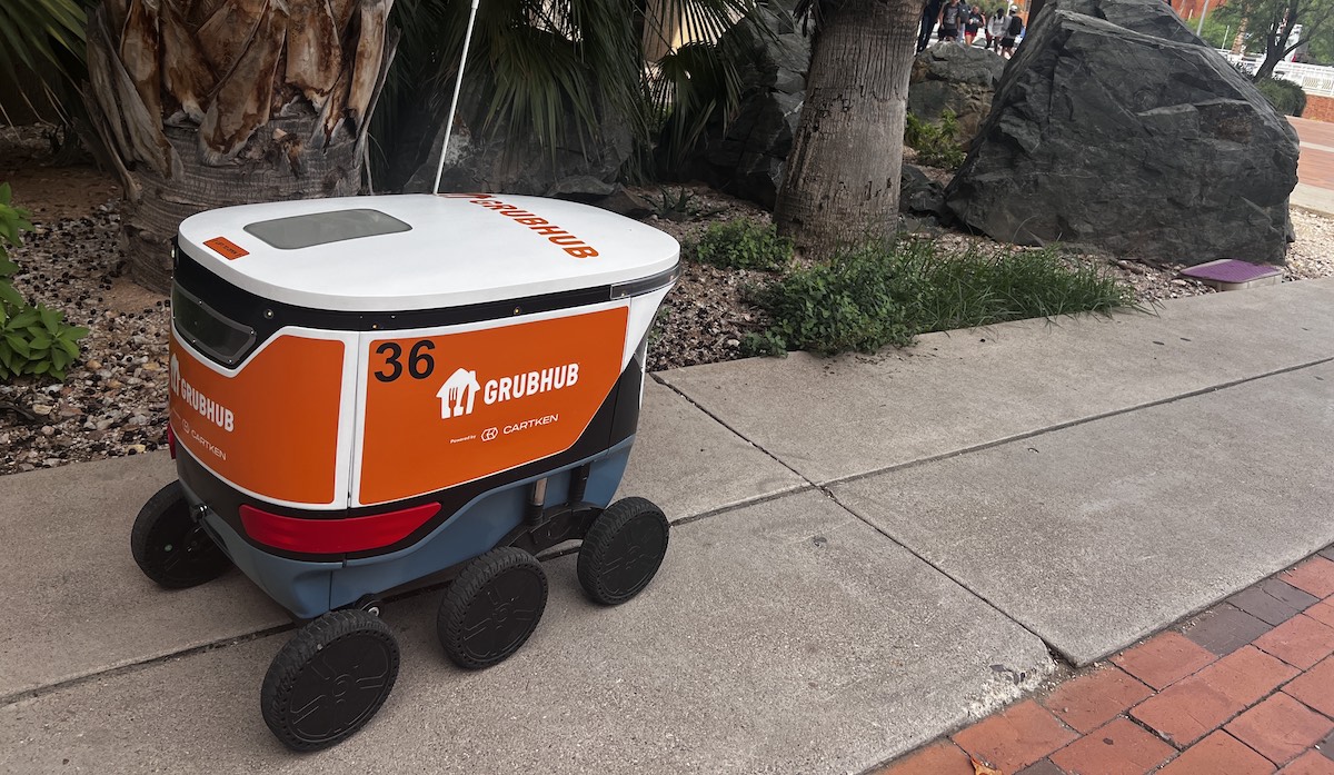 Grubhub and Cartken robot driving through the University of Arizona campus.